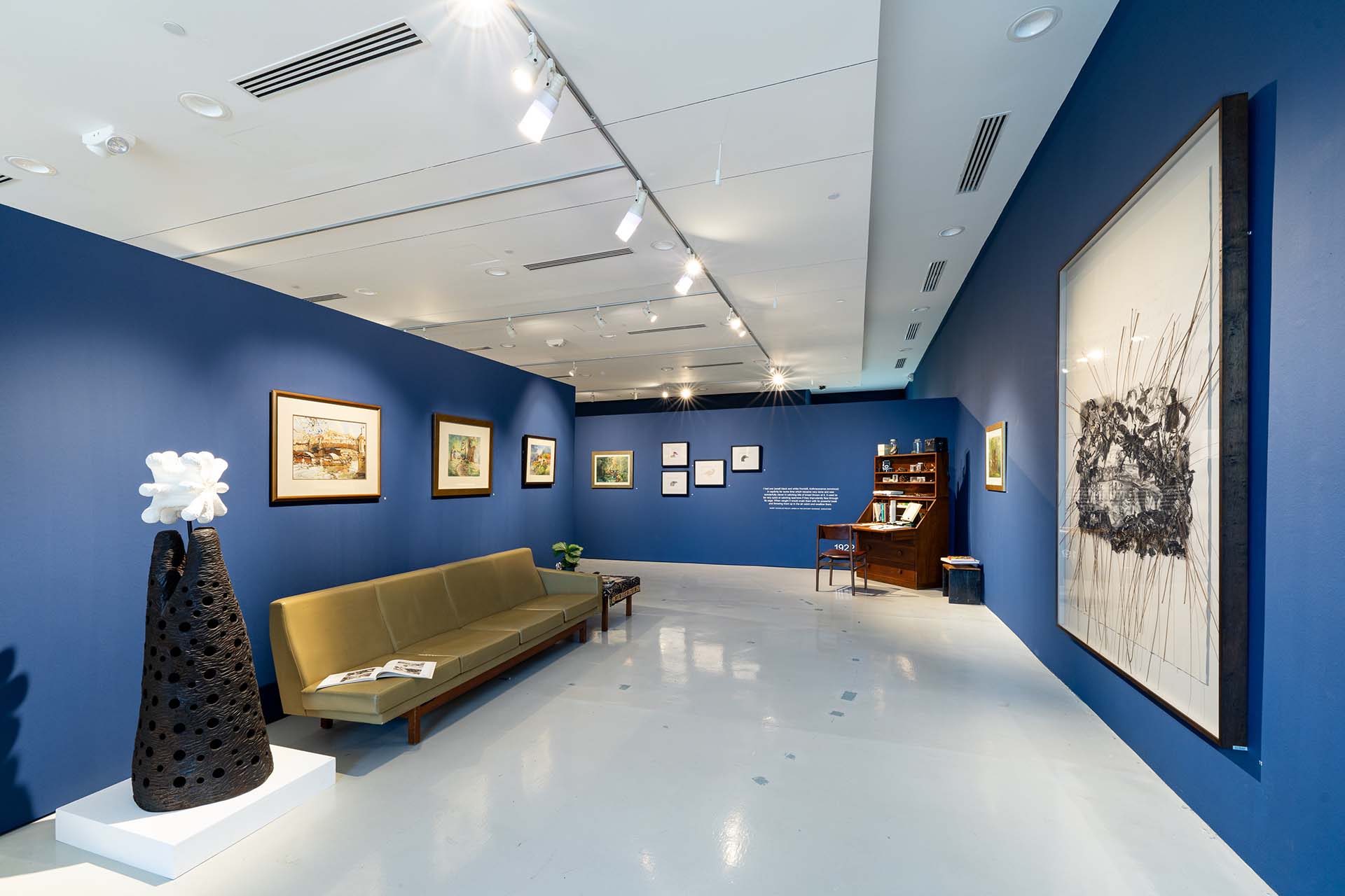 Wideviewofgallerywithartworkonwallsandacouch